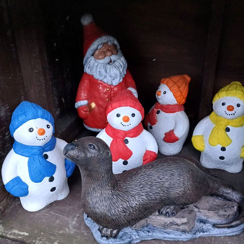Hand-painted Santa, four snowmen in blue, red, orange and yellow hats and scarves, and an otter on a log